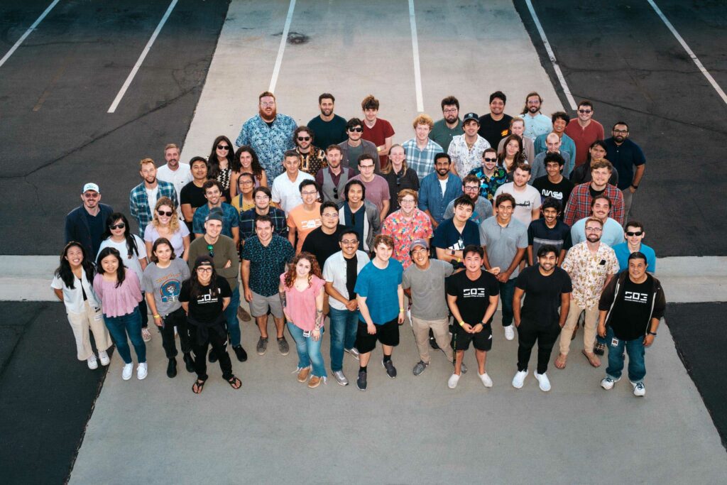 An aerial view of Second Order Effects employees. Pictured are about 75 people standing and looking up at the camera. 